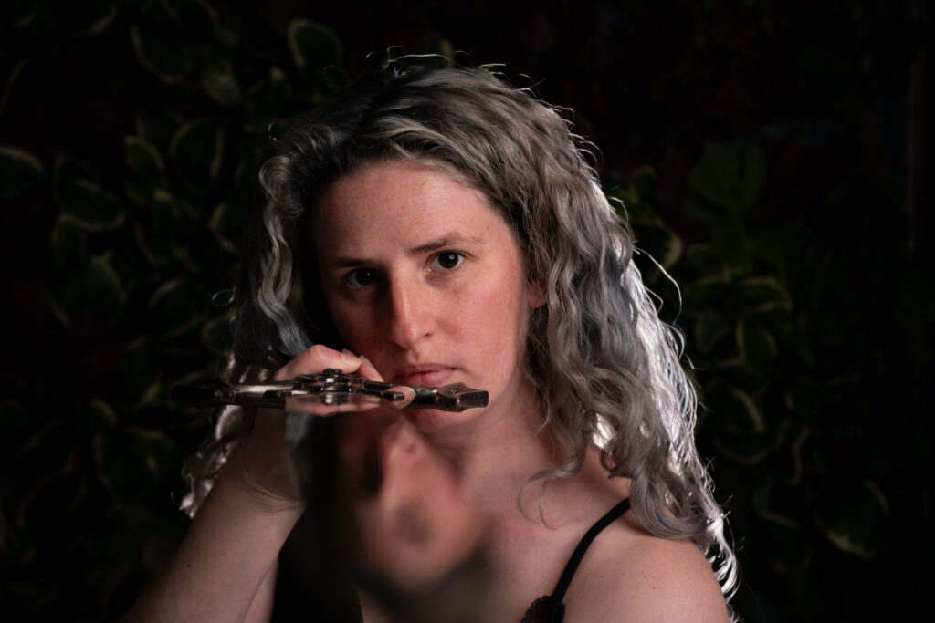 woman looking down a sword toward the camera