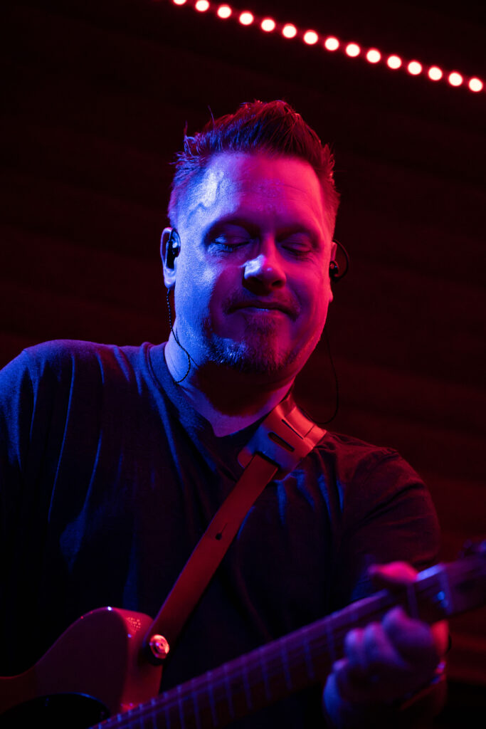 man playing guitar with blue and magenta colorful lights